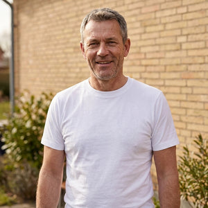 Basic T-shirt, Hvid - 2000 | Livsstilsfoto af en veltrænet mand omkring 55 år med kortklippet gråt/salt-og-peber hår og skægstubbe, iført en almindelig hvid rundhalset T-shirt uden tryk.