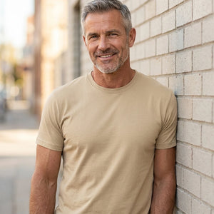 Basic T-shirt, Kit - 2000 | Livsstilsfoto af en veltrænet mand omkring 55 år med kortklippet gråt/salt-og-peber hår og skægstubbe, iført en almindelig hvid rundhalset T-shirt uden tryk.